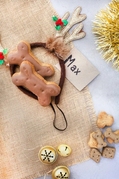 Dog treats for a fantastic pet Christmas treat. Rustic Flat-lay with iced dog biscuit and jingle bells