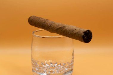 Boş bir bardak ve bej arka planda bir puro..