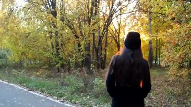 Kız sonbahar parkında yürüyor. Yürü hadi. Hava güzel.
