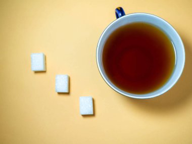 Bej arka planda bir fincan çay, bir parça şeker. Güzel ürün. Çay içiyorum.