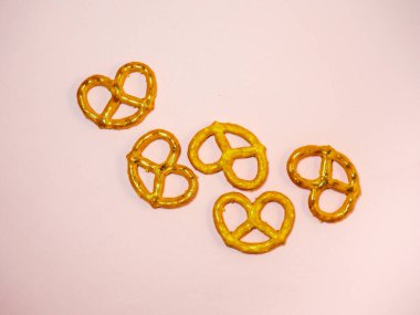 Masanın üzerine bir demet kraker serilmiştir. İlginç bir şekle sahip hamur işleri. Pembe arka planda tuzlu krakerler. Un ürünü. Çay için nefis bir yemek. Hasır çıtır bisküviler..