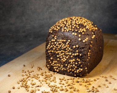 Kişniş serpiştirilmiş siyah ekmek. Borodino ekmeği. Un ürünü. Mutfak tahtasındaki baharatlı ekmek.