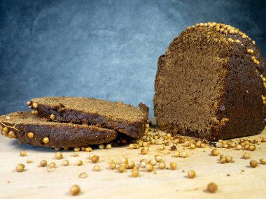 Dilimlenmiş kahverengi ekmek serpiştirilmiş. Sağlıklı beslenme. Borodino ekmeği. Un ürünü. Mutfak tahtasında siyah arkaplanda baharatlar olan ekmek.
