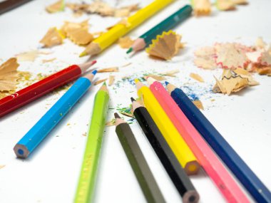 Okul malzemeleri. Kalem açacağı. Kalem açacağı. Beyaz arka planda çok renkli kalemler. Ahşap talaşı. İşe hazırlanma süreci. Yaratıcı mes