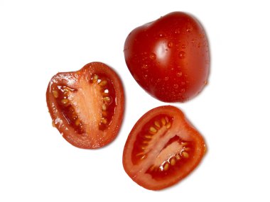 Beyaz arka planda dilimlenmiş erik domatesleri. Kırmızı sebze yalıtımı. Su damlacıklarında taze sebzeler.