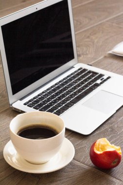 dizüstü bilgisayar, bir fincan kahve ve tahta masanın üzerindeki boş ekran.