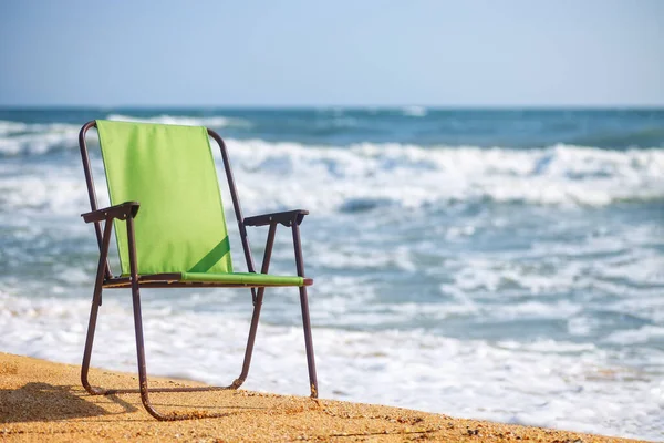 Una sedia pieghevole verde sulla spiaggia del mare — Foto Stock