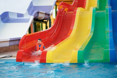Aquapark 'ta su kaydırağındaki küçük mutlu çocuk.