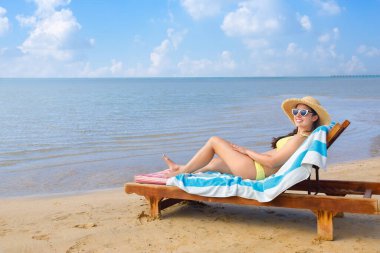 Hasır şapkalı ve güneş gözlüklü genç kadın dinleniyor.