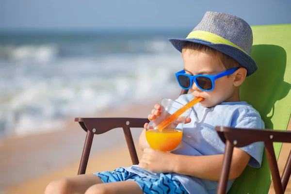 Little boy drinking juice on sea beach — Stock Photo, Image