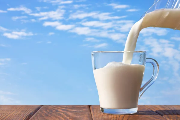 Latte Versato Brocca Tazza Vetro Sul Tavolo Con Cielo Blu — Foto Stock