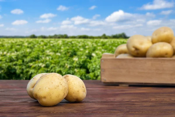 Heap Young Potatoes Wooden Table Crate Blooming Field Background — ストック写真