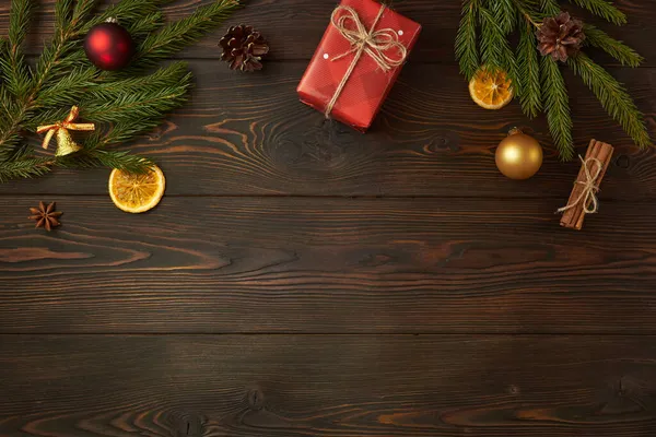 Noel hediyesi ve Noel ağacının dalları koyu ahşap arka planda.