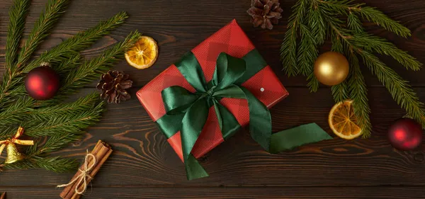 Noel hediyeli Noel afişi, toplar ve koyu ahşap arka planda yeşil ladin dalları.