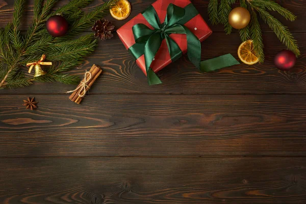 Noel hediyesi ve Noel ağacının dalları koyu ahşap arka planda.