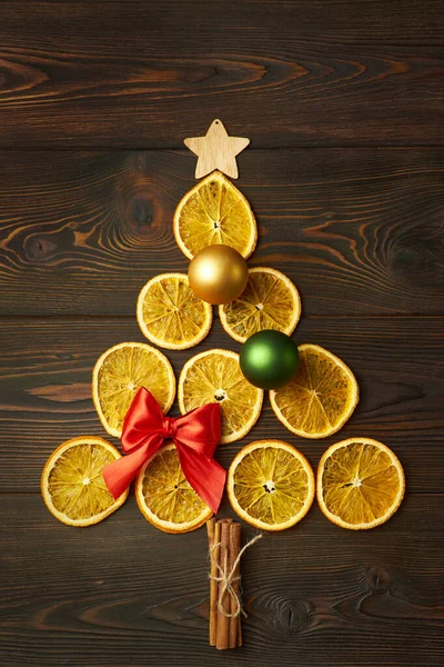 Kuru portakallardan yapılmış Noel ağacı ve koyu kahverengi ahşap bir arka planda Noel mücevherleri. Yaratıcı festival konsepti.