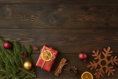 Noel hediyesi ve Noel ağacının dalları koyu ahşap arka planda.