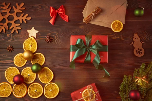 Kuru portakallardan yapılmış Noel ağacı ve koyu kahverengi ahşap arka planda Noel hediyeleri. Yaratıcı dekorasyon kavramı.