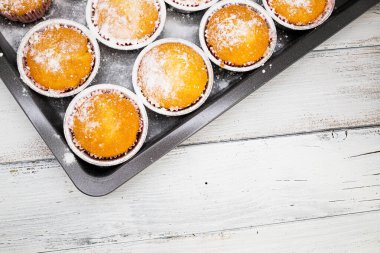 Beyaz ahşap masa üzerinde çeşitli taze pişmiş vanilyalı kekler.