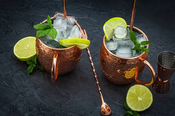 Icy Cold Moscow Mule cocktail in a copper mug with ginger beer, vodka, lime and mint. Grey background.