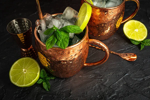 Icy Cold Moscow Mule cocktail in a copper mug with ginger beer, vodka, lime and mint. Grey background.