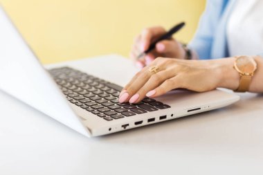 Laptop klavyesinde yazı yazan kadın ellerinin yakın plan portresi, kafede bilgisayarla çalışan genç bir kız. Mavi bir ceket, beyaz bir bluz ve bileğinde saatler vardı. Fotoğraf.