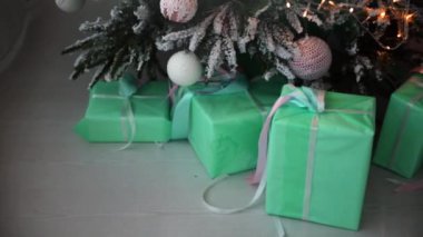Beyaz toplarla süslenmiş bir Noel ağacının yakın çekimi. Noel ağacının altında çok sayıda Noel hediyesi var. Noel tatili kavramı. Tatil arkaplanının altında çok sayıda hediye kutusu var.