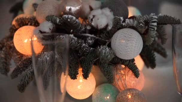 ダイニングテーブルの上の新年の装飾。テーブルにはクリスマスツリーの枝と輝くボールの庭の花瓶が飾られています。. — ストック動画