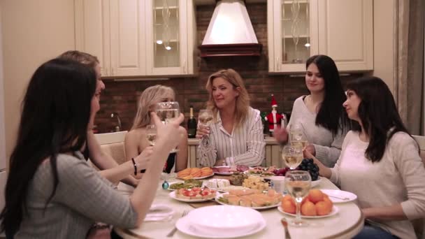 Vidám és boldog barátok társasága ünnepel a karácsonyi vacsorán. A nő felemel egy pohár bort, és köszöntőt mond. — Stock videók