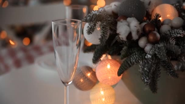 Decoración de Año Nuevo en la mesa de comedor. La mesa está decorada con un jarrón con ramas de árbol de Navidad y una guirnalda de bolas brillantes. — Vídeos de Stock