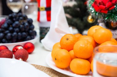 Mandalinalı bir tabak, Yeni Yıl masasında yiyecekle birlikte duruyor. Fotoğraf.