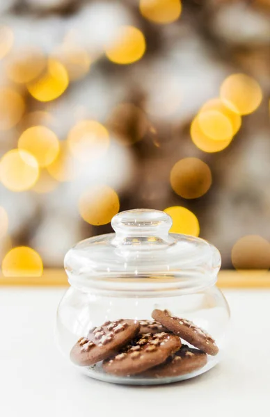 chocolate chip cookies in a jar stand in front of the christmas lights