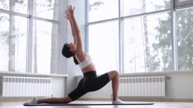 Beyaz bluzlu ve siyah bisikletli kadın yoga yapıyor.