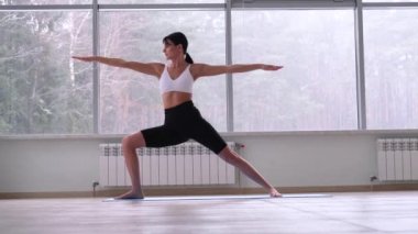 Yoga yapan genç bir Yogi kadını, Savaşçı 2 egzersizi yapıyor.,