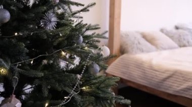 A Christmas tree decorated with toys next to the bed.