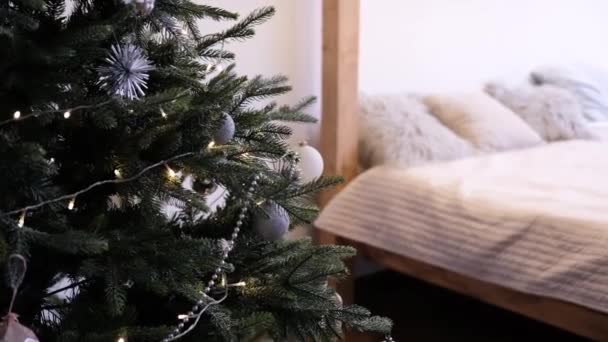 ベッドの横の部屋には おもちゃやガーランドで飾られたクリスマスツリーが立っています 夜のクリスマスの雰囲気 — ストック動画
