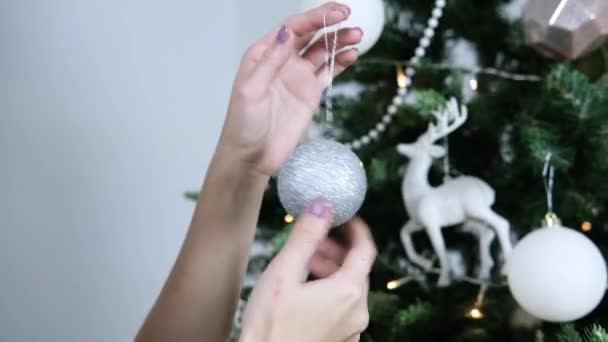 女性の手は銀のクリスマスボールを彼らの手でひねる 女の子はクリスマスツリーを飾る — ストック動画