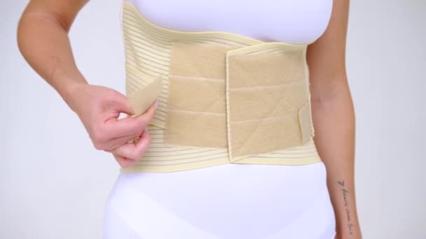 Woman Wearing Beige Support Belt Isolated White Girl Fastens Belt — стоковое видео