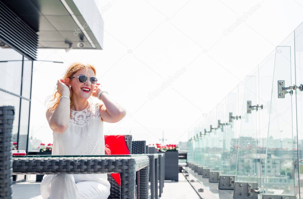 Portrait mature woman smiling enjoying a beautiful sunny day in a cafe outside. Copy space