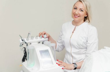 Kadın dermatolog elinde bir güzellik makinesiyle ofisinde poz veriyor. Yatay fotoğraf