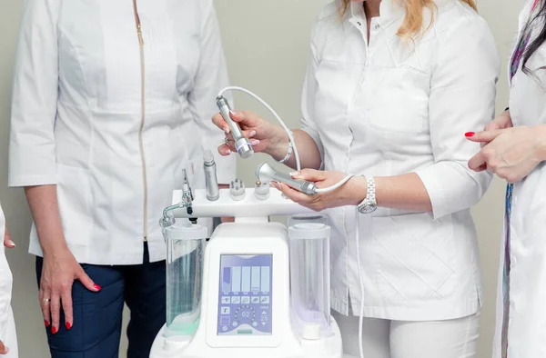 Woman Beautician Demonstrates Her Colleagues How Cosmetic Machine Its Nozzles Stock Photo