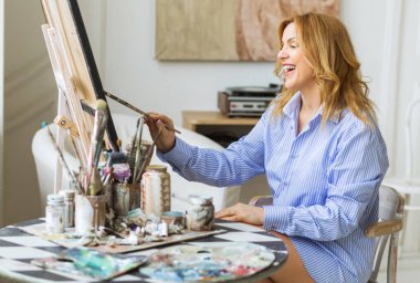 Stüdyoda tuvale fırça süren olgun bir kadın. Hobi ve ruh sağlığı konsepti