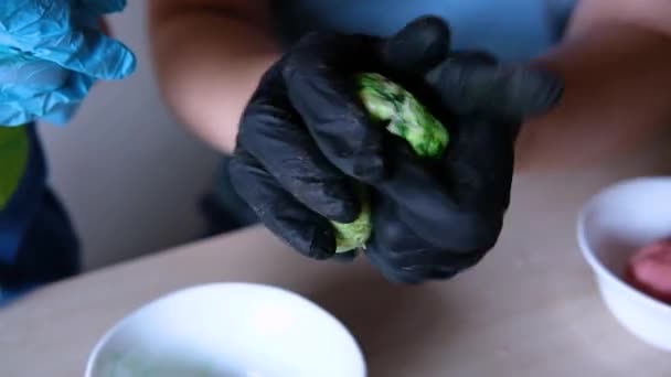 Mulheres mãos em luvas amassar a massa com corante alimentar — Vídeo de Stock