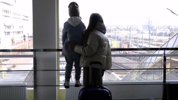 Mãe e filha ficam em frente a uma grande janela no prédio da estação — Vídeo de Stock