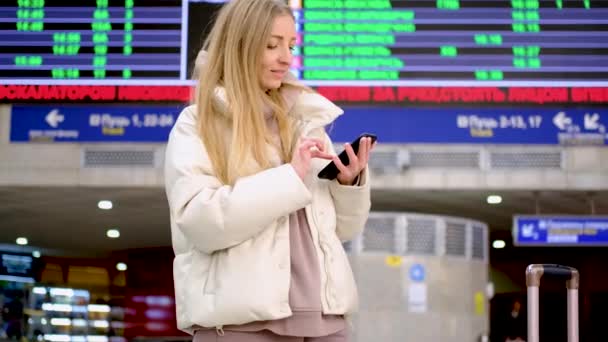 Wanita menonton papan kedatangan dan memeriksa penerbangan — Stok Video