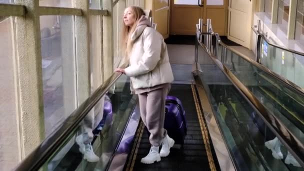 Kaukázusi lány alkalmi dzsekit visel, és a bőröndöt cipeli. — Stock videók