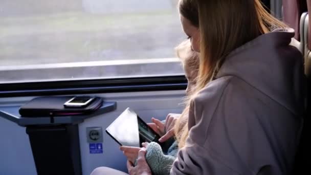 Anne ve kızı trene binip tablette çizgi film izliyorlar. — Stok video
