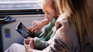 Anne ve kızı bir trene binip bir tablette oyun oynuyorlar. Minsk, Belarus, 10 Aralık 2021.