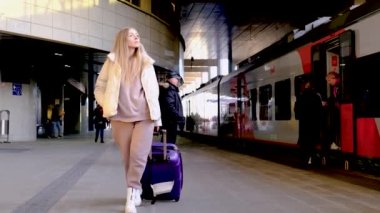 Elinde bavul olan genç bir kadın platformda yürüyor ve arabasını arıyor - Minsk, Belarus, 20 Aralık 2021