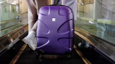 Yürüyen merdivende bavuluyla yürüyen tanınmayan genç bir kadın.. 